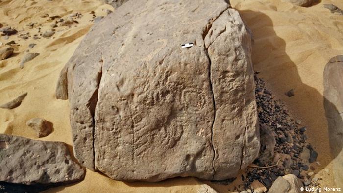 Ancient Egyptian hieroglyphs on a rock under the sand: the square of the king of Horus the scorpion, as the writing says.