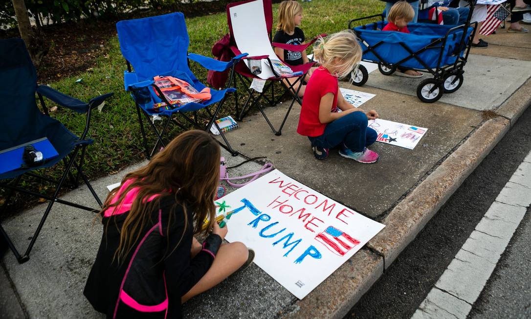 Children of Donald Trump supporters paint posters for an event as they pass by the entourage of Donald Trump supporters who decided not to attend the inauguration of elected political opponent Joe Biden, and spend time with his family at home in Mar-A-Logo Golf Club in Palm Beach, Florida A / G