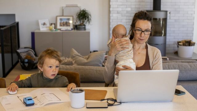 A woman working from home with children by her side.