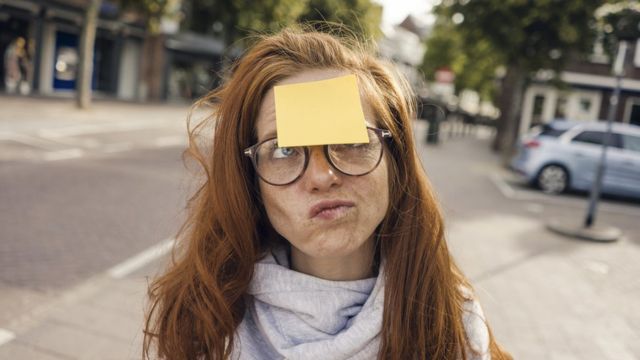 Woman holding blank sticky notes on her forehead