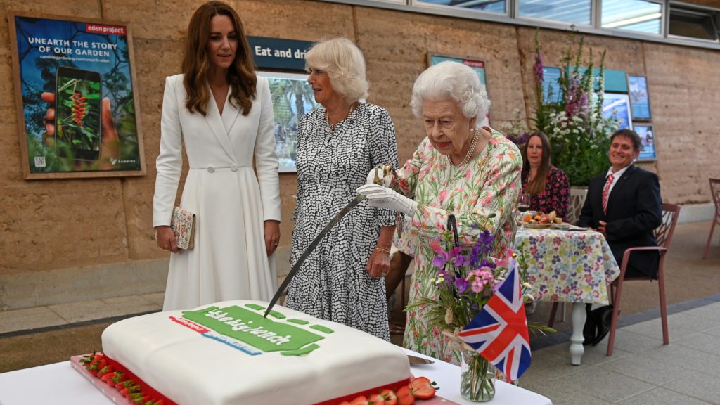 Queen Elizabeth uses the sword to cut the cake during the event