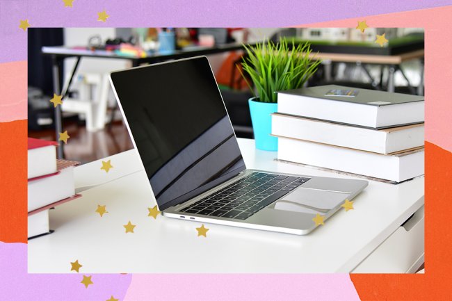 In the photo, a computer is shown under a desk next to some books and a plant.