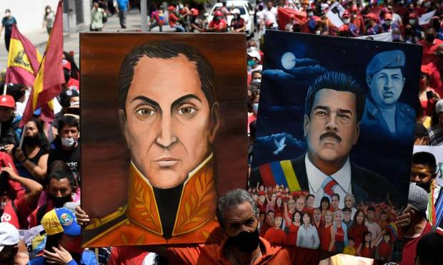 A supporter of Venezuelan President Nicolas Maduro displays selfies of himself and Venezuelan liberator hero Simon Bolivar during a rally to commemorate the Day of Resistance of Indigenous Peoples in Caracas. Photo: FEDRICO PARRA / AFP
