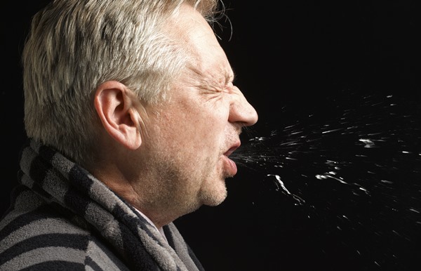 In the color image, the man is shown on the left.  sneezes