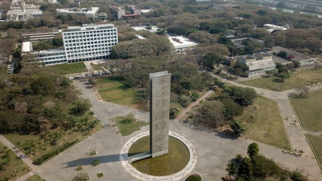 The color photo shows an aerial view of Praça do Relógio, a spacious plaza with a modern tower in the center