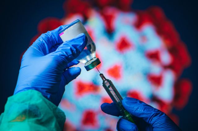 Hand holding blue glove syringe and vial with vaccine